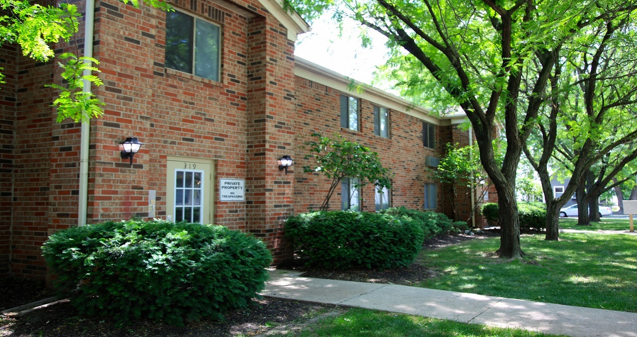 the side of a brick building with trees and a sidewalk